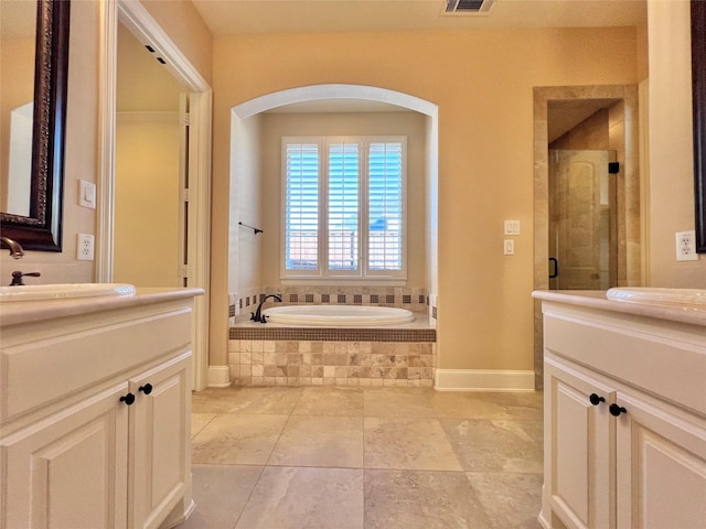 bathroom with a garden tub, a shower stall, two vanities, and a sink