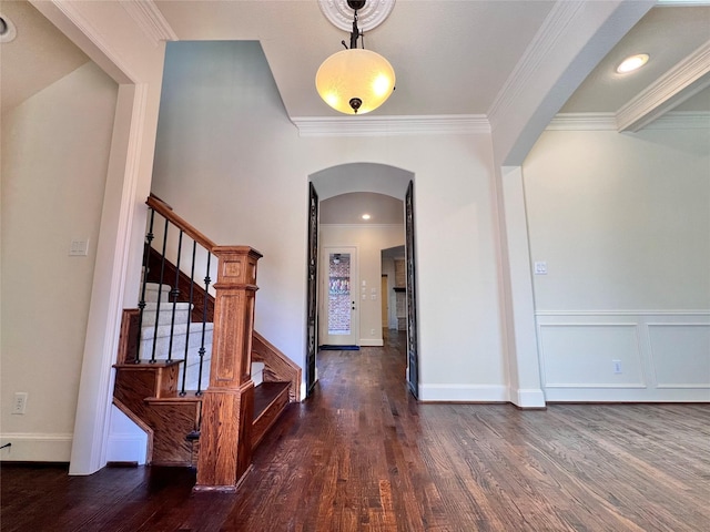 foyer featuring dark wood-style floors, stairs, arched walkways, and crown molding