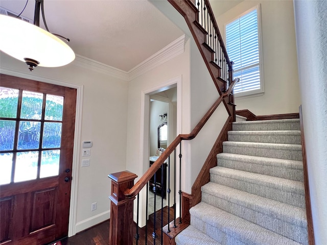 foyer entrance featuring ornamental molding, dark wood-type flooring, stairway, and baseboards