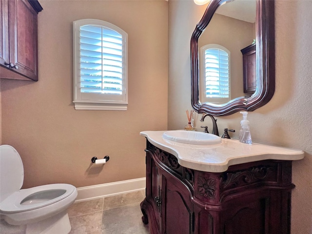 half bath featuring baseboards, vanity, toilet, and tile patterned floors