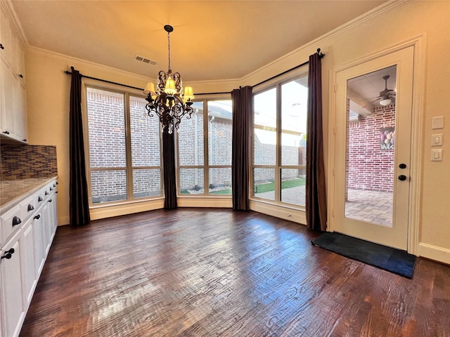 unfurnished dining area featuring ornamental molding, visible vents, dark wood finished floors, and an inviting chandelier