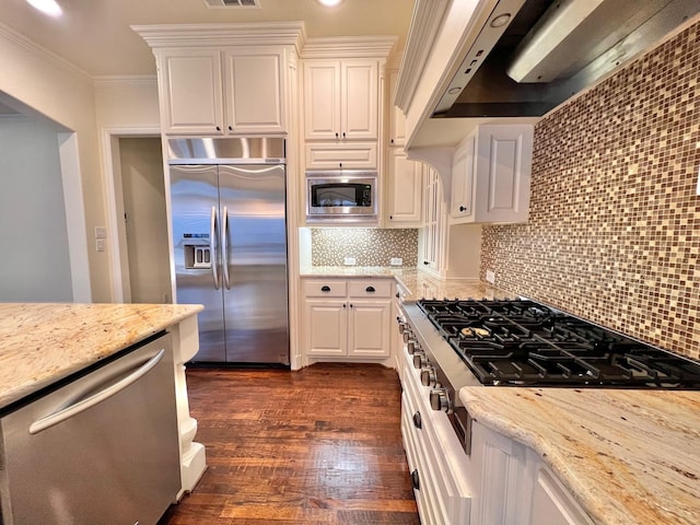 kitchen featuring exhaust hood, white cabinetry, crown molding, and built in appliances