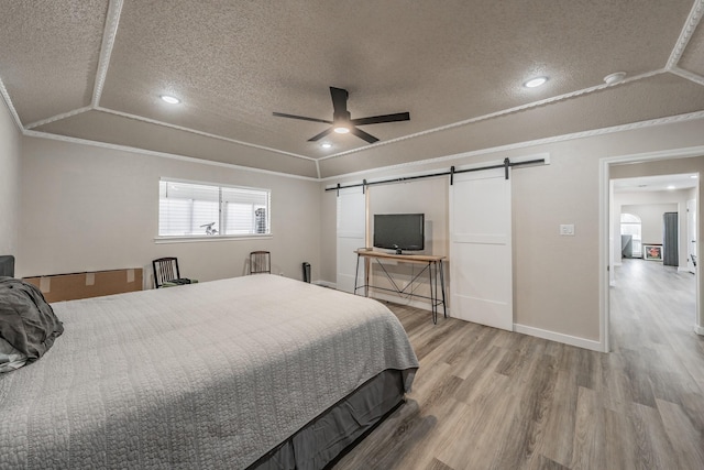 bedroom featuring crown molding, a barn door, a textured ceiling, and light wood-style floors