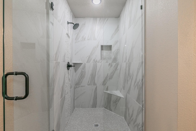 full bathroom featuring a textured ceiling, a textured wall, and a shower stall