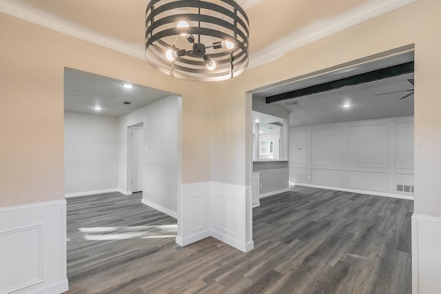 spare room featuring dark wood-style flooring, visible vents, and a decorative wall