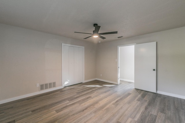 unfurnished bedroom featuring wood finished floors, visible vents, and baseboards