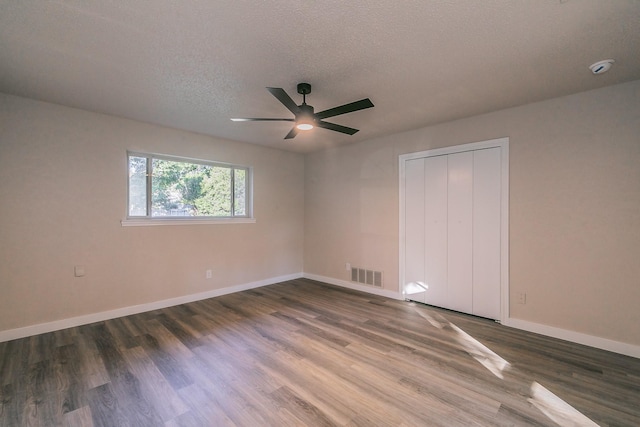 unfurnished bedroom featuring baseboards, visible vents, ceiling fan, dark wood-type flooring, and a textured ceiling