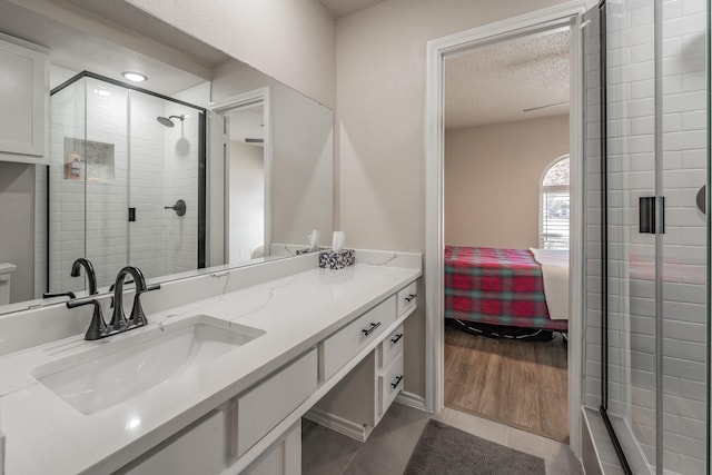 full bathroom featuring a textured ceiling, ensuite bathroom, vanity, tile patterned floors, and a stall shower