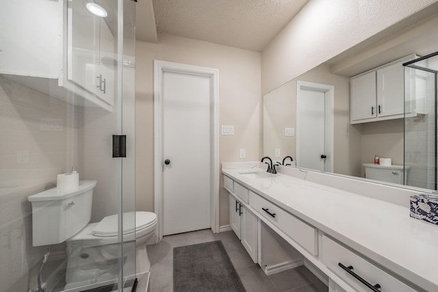 full bath featuring a stall shower, vanity, toilet, and a textured ceiling