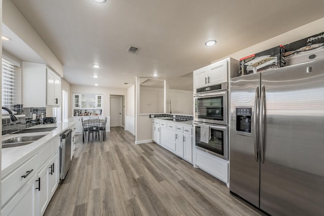 kitchen with visible vents, appliances with stainless steel finishes, light wood-style floors, white cabinetry, and a sink