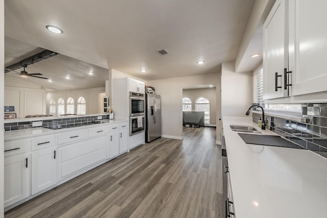 kitchen with stainless steel appliances, a sink, white cabinets, and decorative backsplash