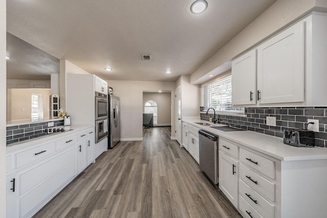 kitchen with white cabinetry, appliances with stainless steel finishes, a sink, and wood finished floors