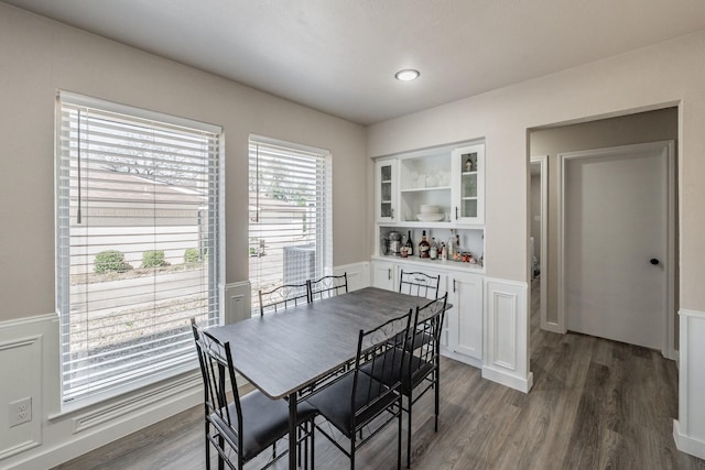 dining space featuring a wainscoted wall, built in shelves, and wood finished floors