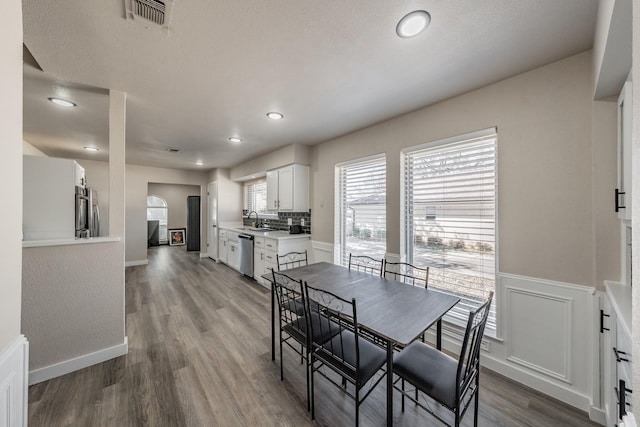 dining room with a wainscoted wall, recessed lighting, visible vents, wood finished floors, and baseboards