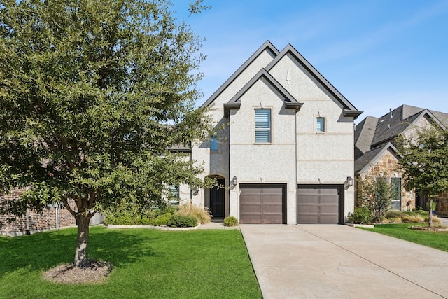 french provincial home featuring an attached garage, concrete driveway, and a front yard