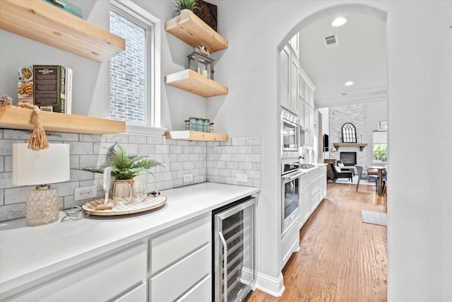 kitchen featuring light wood finished floors, white cabinets, wine cooler, stainless steel oven, and open shelves