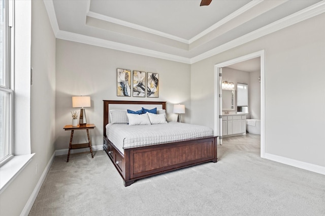 bedroom featuring light carpet, baseboards, a tray ceiling, and ensuite bathroom