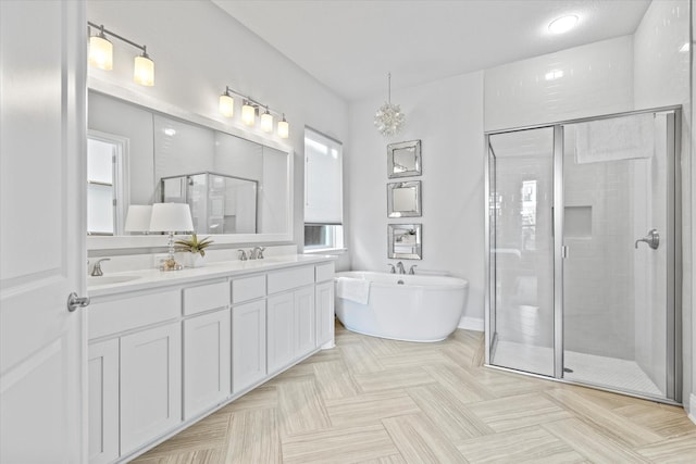 bathroom featuring a freestanding bath, double vanity, a stall shower, and a sink