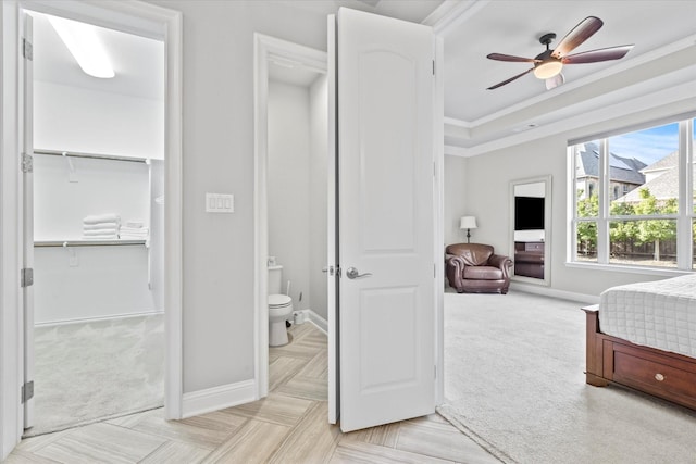 bedroom with baseboards, a raised ceiling, light colored carpet, and crown molding