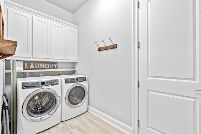 laundry room featuring cabinet space, light wood-style flooring, baseboards, and separate washer and dryer