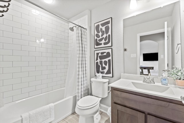 bathroom featuring a textured wall, toilet, wood finished floors, vanity, and shower / bath combo