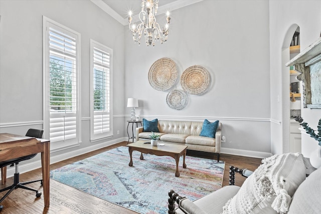 living room featuring ornamental molding, a notable chandelier, baseboards, and wood finished floors