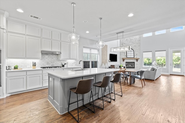 kitchen with gas cooktop, light wood-style flooring, a sink, visible vents, and light countertops