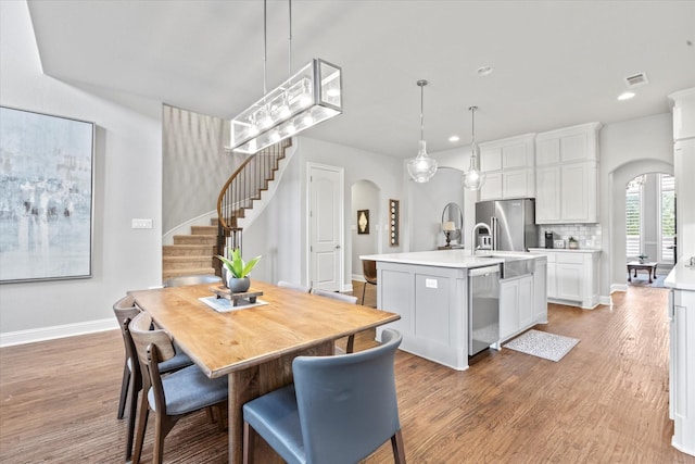 dining room with visible vents, stairs, arched walkways, and light wood-style flooring