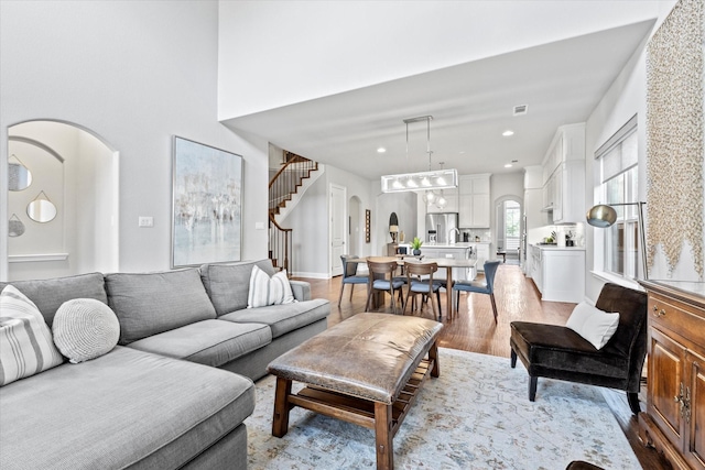 living area with visible vents, arched walkways, stairs, light wood-style floors, and recessed lighting