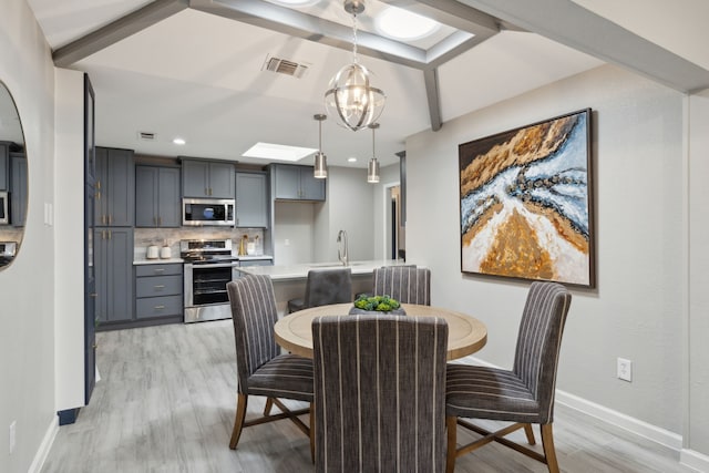 dining room featuring baseboards, light wood finished floors, visible vents, and a notable chandelier