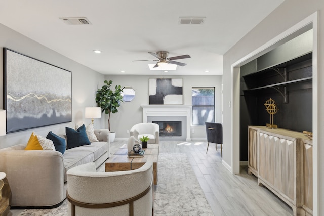 living area with wood finish floors, visible vents, a glass covered fireplace, and recessed lighting