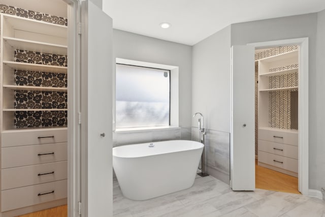 full bath featuring a freestanding tub and marble finish floor