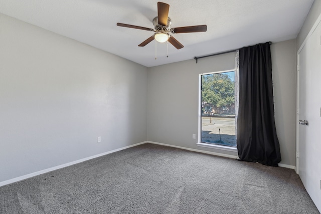 carpeted empty room featuring ceiling fan and baseboards