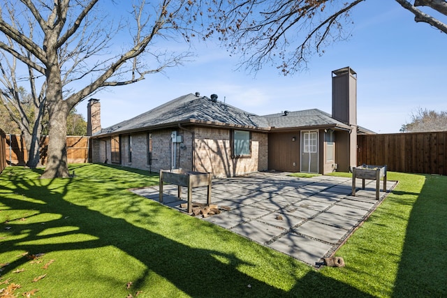 back of property with a patio area, a chimney, a lawn, and brick siding