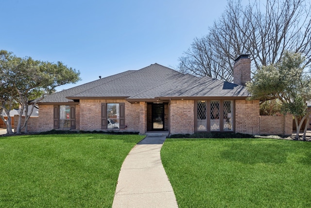 single story home with roof with shingles, a front lawn, and brick siding