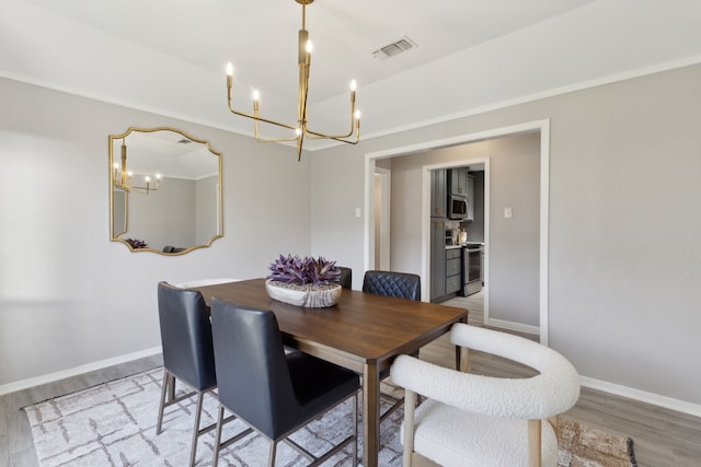 dining area featuring light wood finished floors, baseboards, visible vents, and a chandelier