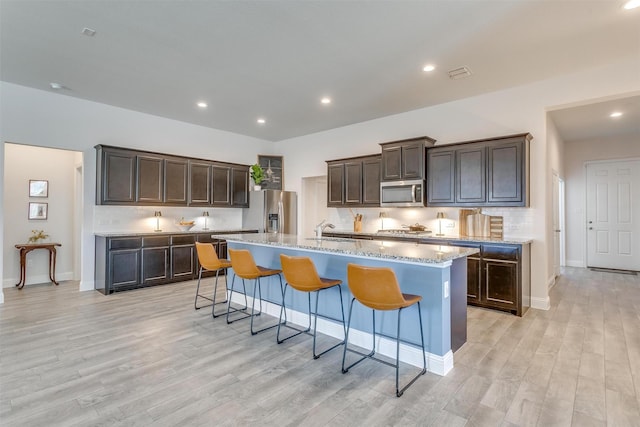 kitchen featuring light wood-style floors, visible vents, appliances with stainless steel finishes, and a breakfast bar