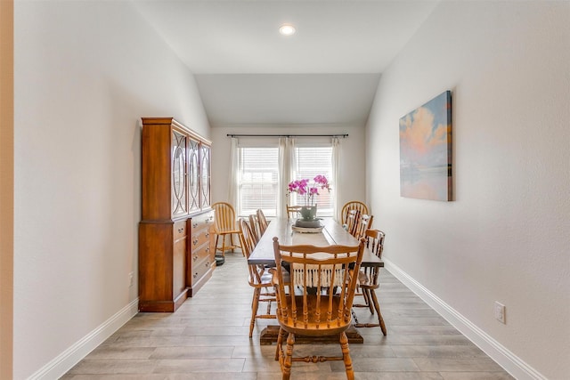 dining room with lofted ceiling, light wood-style flooring, and baseboards