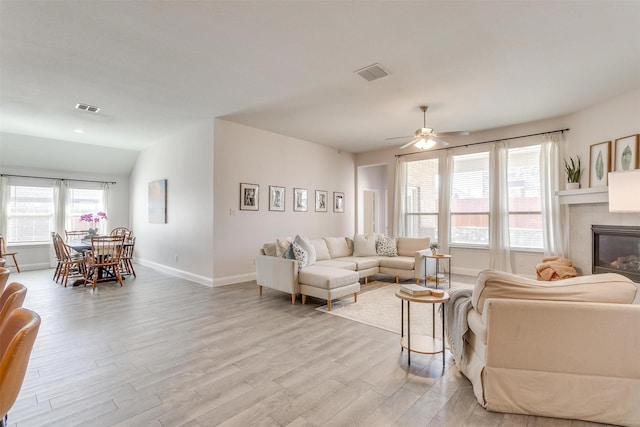 living area with light wood-style floors, baseboards, visible vents, and a tile fireplace