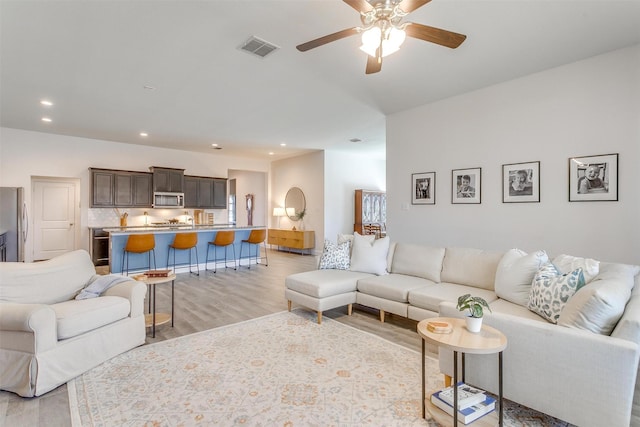 living room featuring light wood-type flooring, visible vents, ceiling fan, and recessed lighting