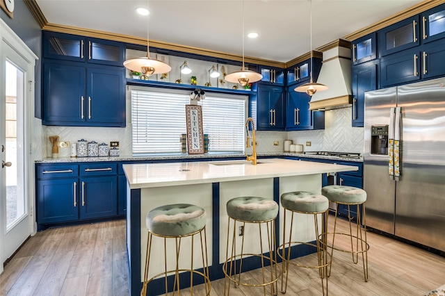 kitchen with blue cabinetry, a breakfast bar area, a sink, and stainless steel fridge with ice dispenser