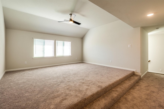 spare room featuring vaulted ceiling, carpet flooring, a ceiling fan, and baseboards