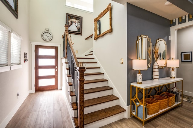 entrance foyer featuring a towering ceiling, baseboards, stairway, and wood finished floors