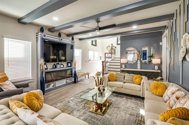 living room with beam ceiling, recessed lighting, stairway, a glass covered fireplace, and wood finished floors