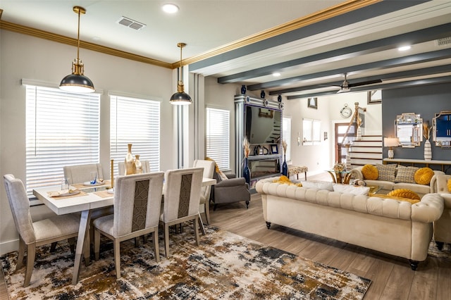 living area featuring wood finished floors, visible vents, stairs, beam ceiling, and crown molding