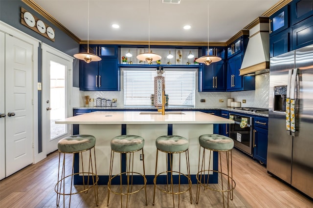 kitchen featuring stainless steel appliances, premium range hood, a kitchen bar, and blue cabinets