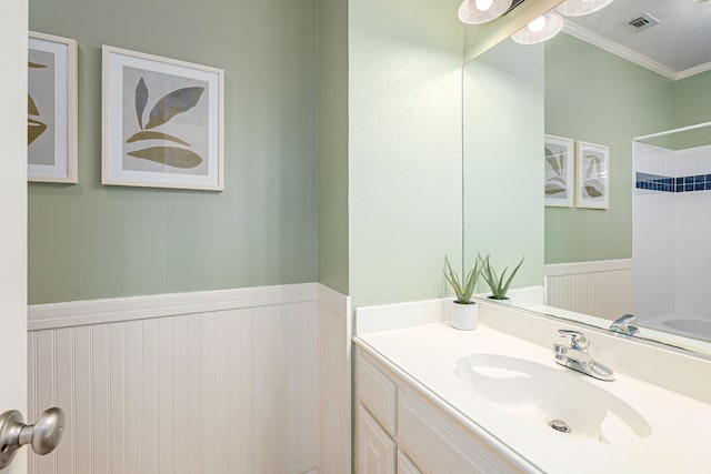 full bathroom featuring ornamental molding, a wainscoted wall, visible vents, and vanity