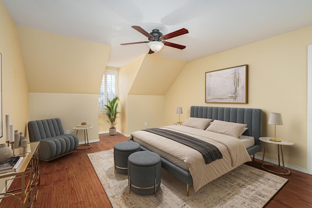 bedroom with a ceiling fan, vaulted ceiling, baseboards, and wood finished floors