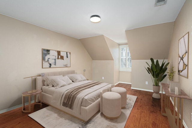 bedroom featuring lofted ceiling, baseboards, visible vents, and wood finished floors