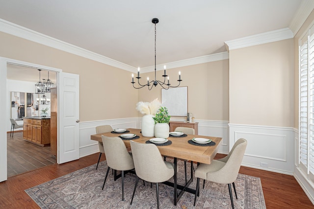 dining space featuring ornamental molding, wainscoting, dark wood finished floors, and a notable chandelier